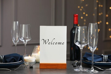 Holder with word Welcome on table set for couple in restaurant