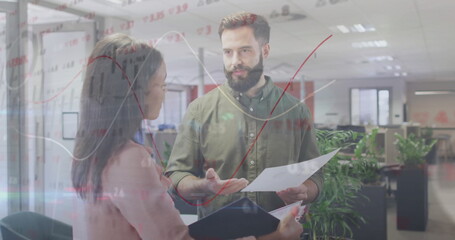 Gesturing colleagues discussing graphs at glass partition, with printed sheet and dark folder