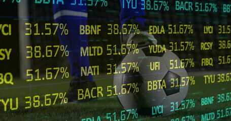 Obraz premium Poising soccer player's cleated foot pressing on ball on grass field, with stock ticker overlay