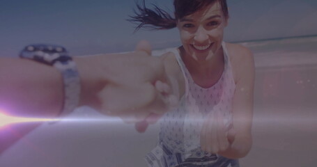Running mid adult woman wearing sundress holding hand on beach, with wristwatch, sunscreen streak