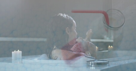 Relaxing adult woman sipping from ceramic mug in freestanding tub, with lit candles and straw jar