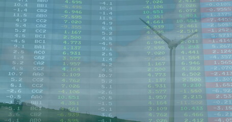 Spinning wind turbine turning three blades on rural hillside, with overlaid market data graph