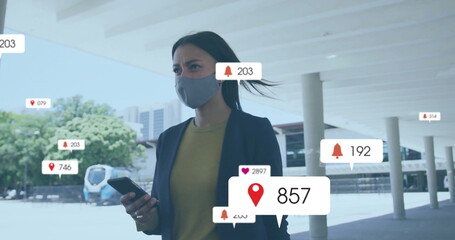Standing Hispanic woman holding smartphone, wearing blazer and mask under canopy, viewing AR icons