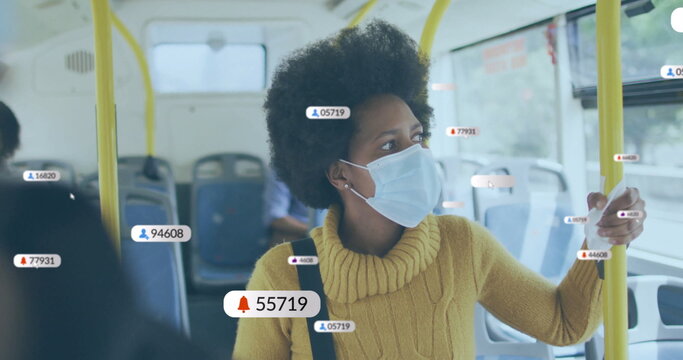 Standing woman wearing yellow sweater and mask holding handrail in bus aisle, with digital overlay
