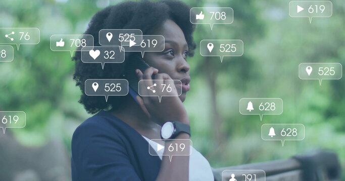 Holding smartphone to ear, woman viewing AR-style social media metrics in park, showing smartwatch - Powered by Adobe