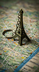 Eiffel tower keychain resting on a detailed map with blue lines and street names visible