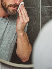 Man Cleansing His Face in Bathroom Mirror During Morning Routine for Healthy Skin Care Practice