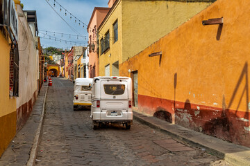 Cobblestone street in Bernal Mexico with colorful buildings and two mototaxis