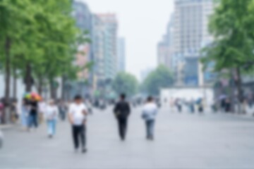 A blurred view of a bustling street in Hangzhou, China. People walk through the city as tall...