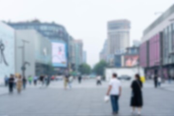 Obraz premium A blurred view of people walking on a paved street in a city with tall buildings.