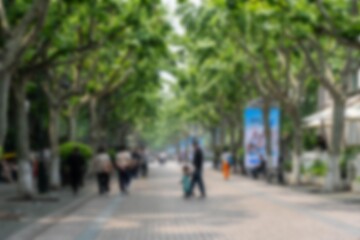 A blurred image of a street lined with trees in Hangzhou, China.