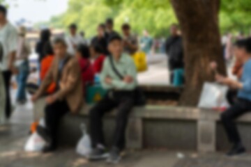 A blurred image of people sitting and standing in a park, likely in Hangzhou, China.