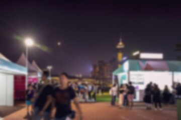 Obraz premium A blurry night scene in Hong Kong, China. The focus is on people walking past street vendors with a blurred background of city lights.