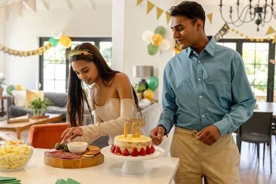 Diverse couple preparing party treats on kitchen island with strawberry cake and charcuterie board - Powered by Adobe