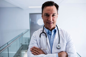 Stethoscope resting on white lab coat draping across glass railing in sleek hospital corridor