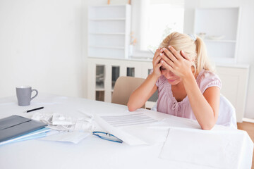 Spreadsheets and receipts are covering dining table near window, with eyeglasses and coffee mug