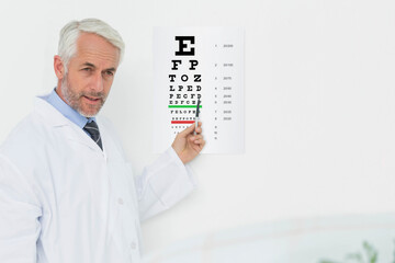 Senior male optometrist holding pointer and pointing at Snellen eye chart in exam room, copy space