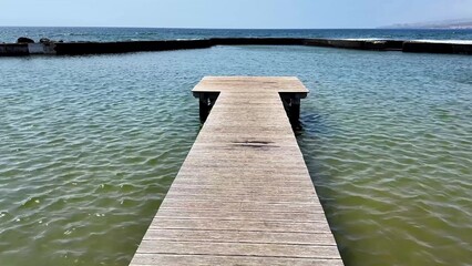 A peaceful wooden dock gracefully extending over calm, serene waters accompanied by a stunning sky...