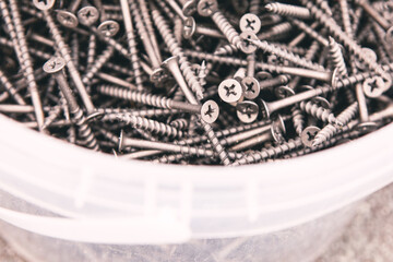 Numerous screws, tightly packed in a white container. Metal screws fill a white bucket, showcasing a dense collection