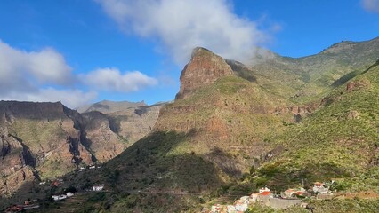A stunning landscape with magnificent mountains, fluffy clouds, and vibrant greenery that...