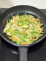 Stir-fried veggies in black frying pan.