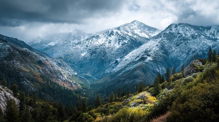 Fototapeta premium Snowy peaks rise over a valley, with fog and colorful autumn foliage below