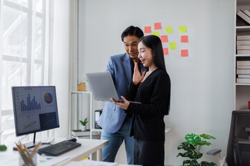 Two asian business man Asian woman using tablet ipad, standing near the window in workplace	
