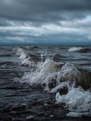 Fototapeta premium Waves Crashing Against the Rocky Shore Under a Moody Sky at Dusk