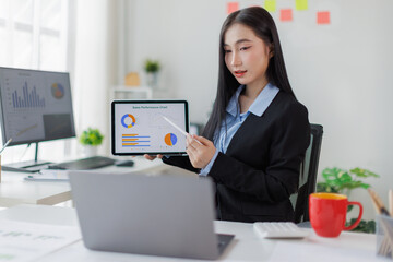 Financial Businesswomen analyze the graph of the company's performance to create profits and...
