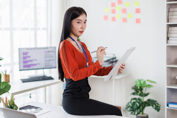 Portrait of Happy young Asian business woman looking at folded.Smiling woman executive manager,secretary offering professional business services standing in office.
