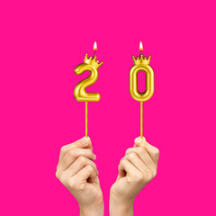 Birthday on a fuchsia background with the number 20 - Hands holding number-shaped candles