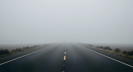 Fototapeta premium An empty asphalt road disappearing into thick, dense fog.
