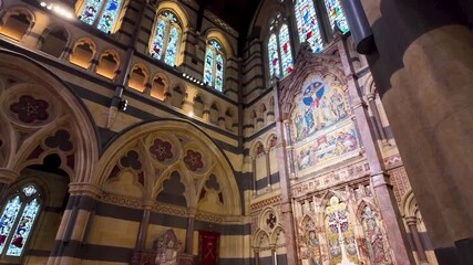 Interior view of St Paul's Cathedral in Melbourne, Australia, featuring the high alta, ornately decorated reredos adorned with biblical mosaics, stained glass windows, and soaring arches - Powered by Adobe
