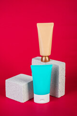 Cosmetic cream tube and skin care or sunscreen cosmetic with stylish propson red background.