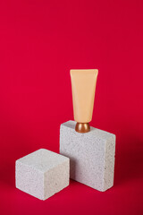 Cosmetic cream tube and skin care or sunscreen cosmetic with stylish propson red background.