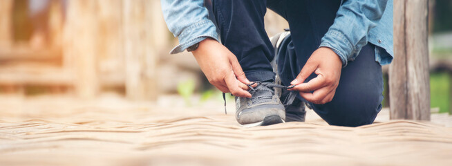 Banner Man kneels down rope tie shoes industry boots for worker. Close up shot of man hands tied...