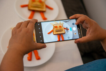 Person Photographing Playful Food Art from a phone camera &ndash; Creative Kids&rsquo; Meal with Vegetable Robot Faces