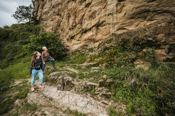 Mother and daughter dressed in hiking clothes, walking along a cliff to find cave paintings.