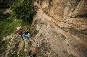 Mother and daughter dressed in hiking clothes, walking along a cliff observing cave paintings.