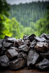 Obraz premium A close-up view of dark stones piled together, with rainwater creating droplets against the rocky surface. The background features lush greenery, enhancing the tranquil atmosphere of the scene.
