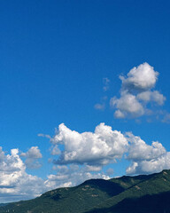 Blue sky with clouds over green hills.