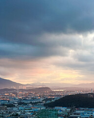 Dusk settles over industrial city under clouds.