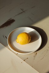 Lemon in Ceramic Bowl on Beige Table. Minimalist composition of a single lemon in a white bowl, perfect for natural or healthy lifestyle themes.
