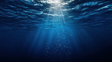 Sunlight streams through ocean waves, creating a mesmerizing play of light and shadow in deep blue waters.