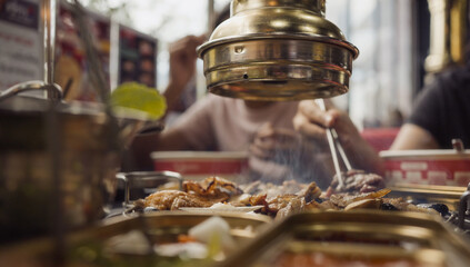 Hand cooking smoked grilled pork on iron grill pan in Korean BBQ in restaurant. Traditional Korea style food barbecue pork belly steak on charcoal grill.