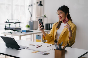 Young asian businesswoman using smartphone and credit card for online shopping at office desk