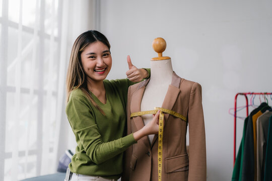 Fashion designer measuring clothes on mannequin and giving thumbs up
