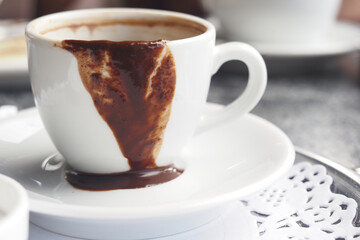 Coffee cup overflowing with melted chocolate in stylish cafe