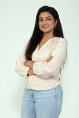 Portrait of an Indian smiling young woman arm crossed isolated on grey studio background