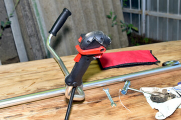 Close-up of the handle of a petrol trimmer with the throttle control lever, ignition switch and...